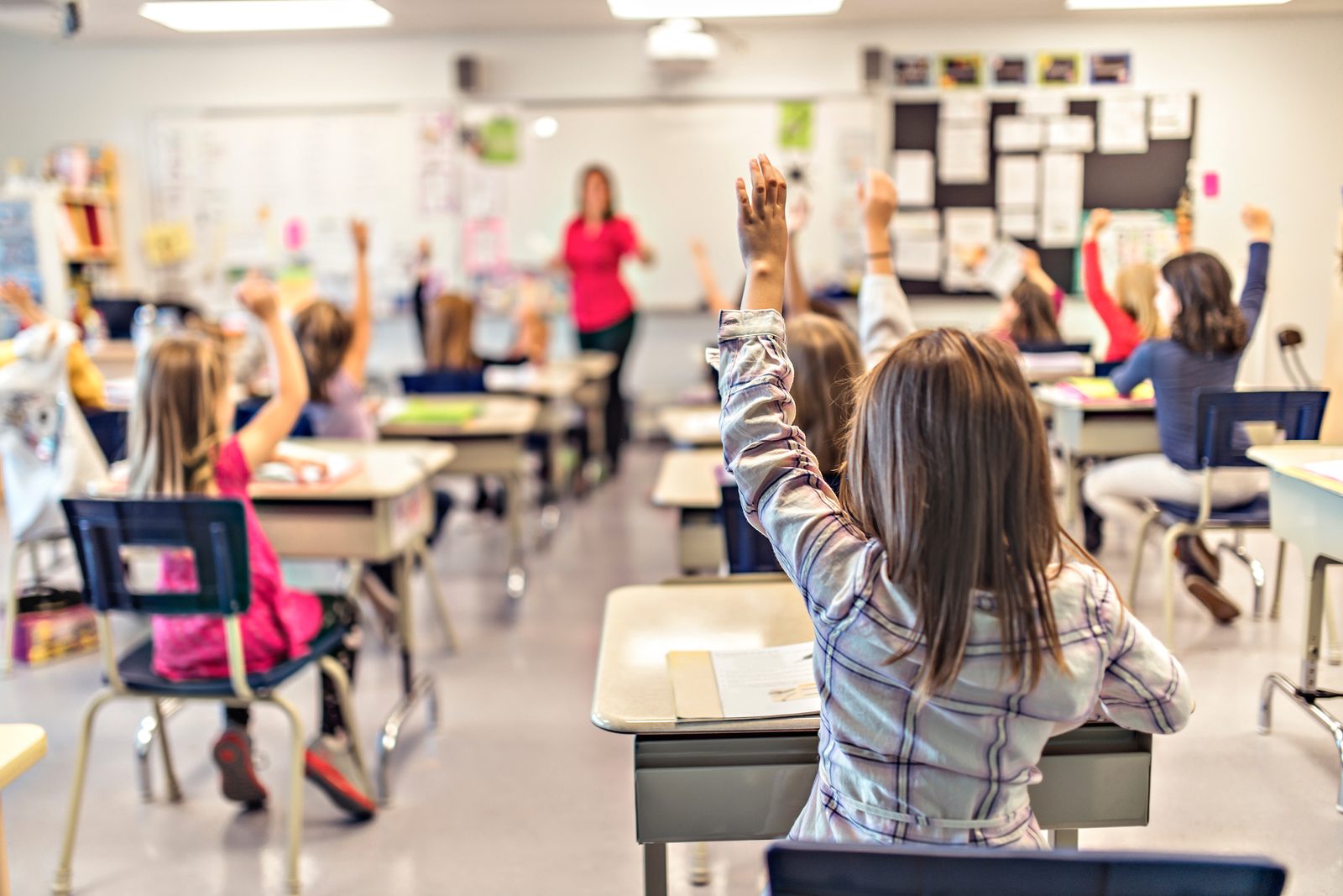 Elementary school classroom with students raising their hands